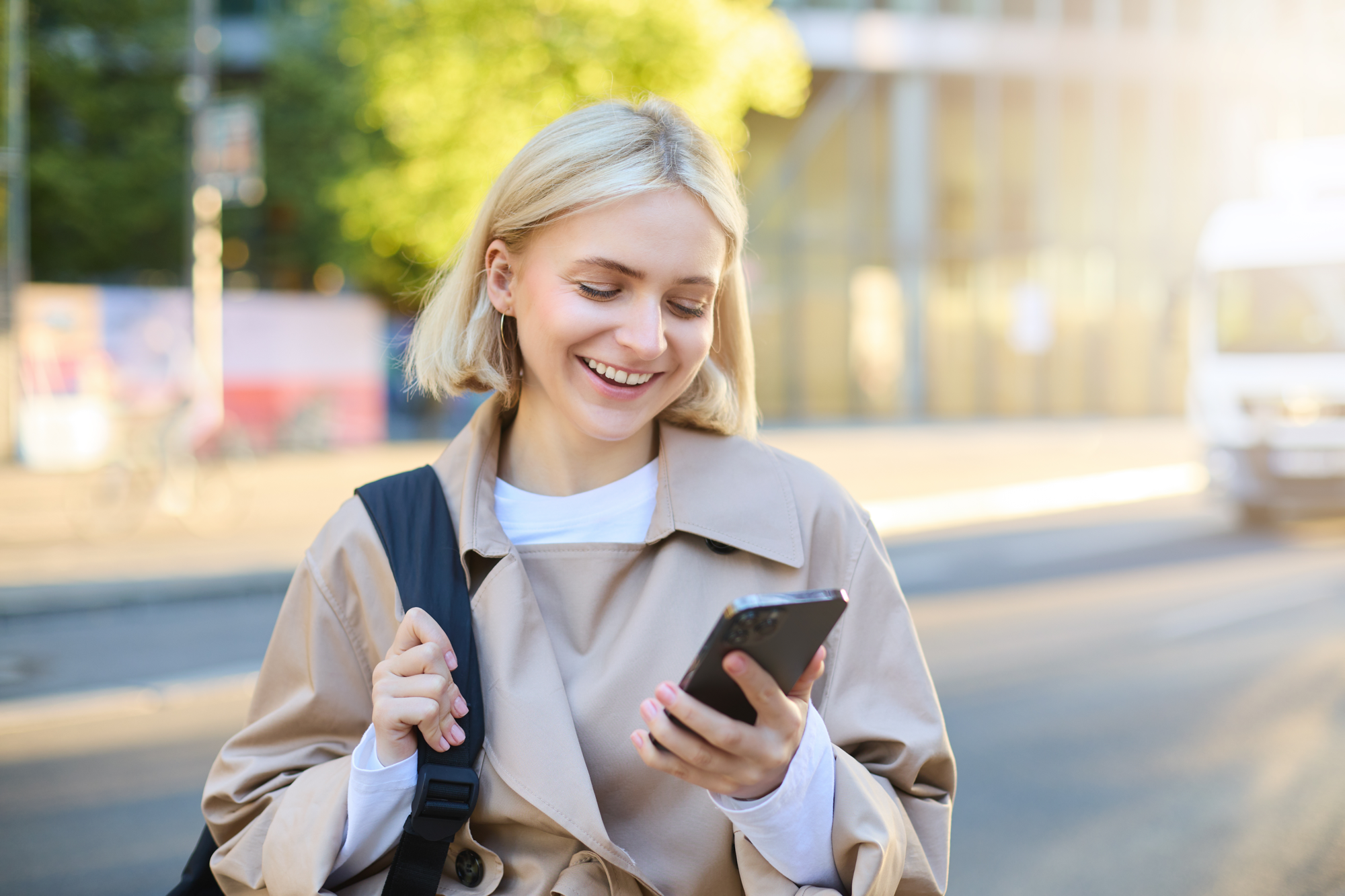 Young woman smiling at her phone while walking outside