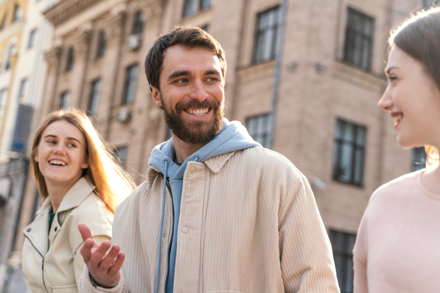 Smiling man talking with two friends outdoors in the city