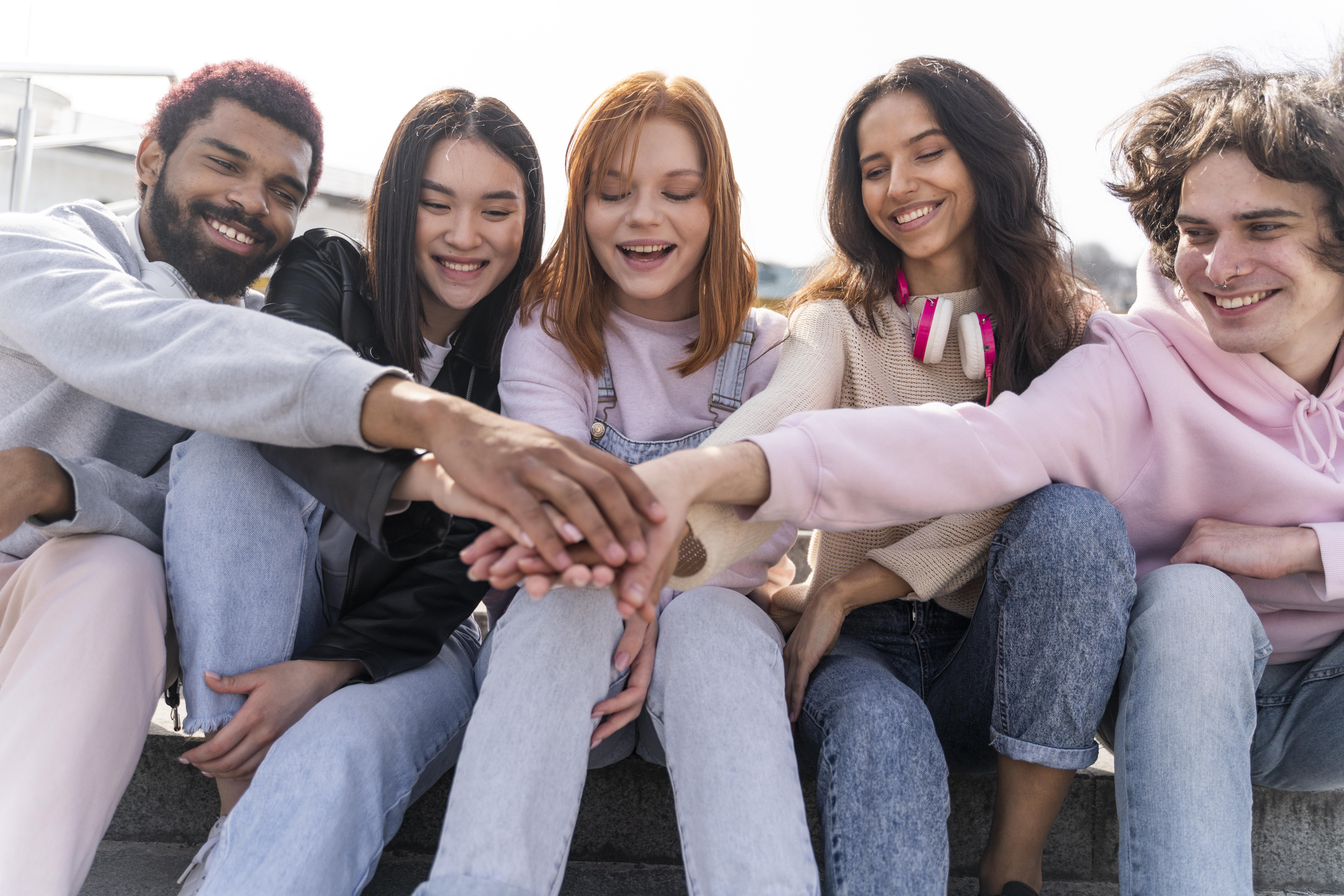 Group of smiling friends in a city, looking at their phones